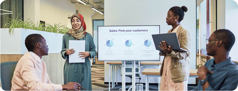 Sales team presenting customer profile charts on a large screen during a strategy meeting